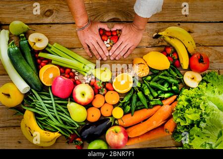 Légumes frais et saisonniers et fruits sur une table de woodem avec les mains de femmes faisant l'amour coeur avec elle - saine alimentation concept de mode de vie pour végétarien ou activité de perte de poids de régime Banque D'Images