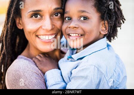 Portrait de famille couple mère et fils noir de race ethnique afro sourire et regarder la caméra - concept de diversité et de mère célibataire avec de jeunes enfants - bonheur et joie concept avec amour - foyer sur les yeux des enfants Banque D'Images