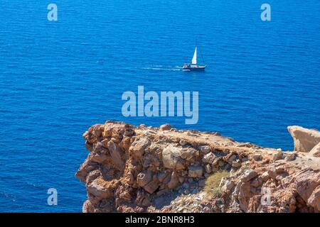 Temps ensoleillé sur une côte rocheuse. Falaise calcaire. Yacht solitaire dans la mer bleue Banque D'Images