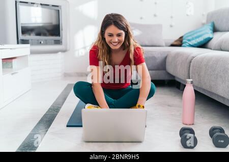femme faisant du sport sur un tapis suivant des cours en ligne avec un ordinateur portable à la maison Banque D'Images
