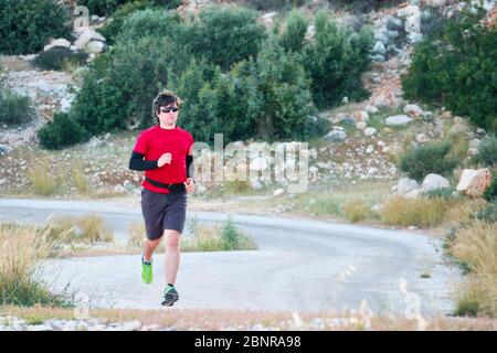 jeune homme portant des lunettes de soleil lors d'un jogging matinal à la campagne. Banque D'Images