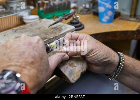 Production de bijoux. Un bijoutier polit une bague or sur un vieux établi dans un atelier de bijoux authentique Banque D'Images