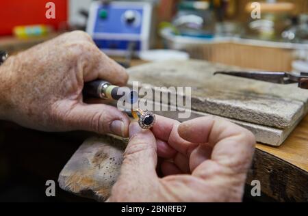 Production de bijoux. Un bijoutier polit une bague or sur un vieux établi dans un atelier de bijoux authentique Banque D'Images