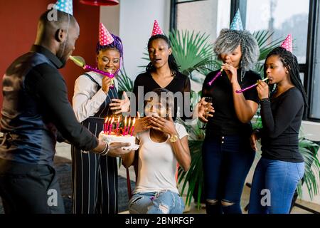 Des adolescents africains avec des cornes de fête et un gâteau célébrant un anniversaire Banque D'Images