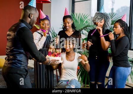 Des adolescents africains avec des cornes de fête et un gâteau célébrant un anniversaire Banque D'Images