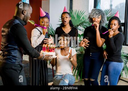 Des adolescents africains avec des cornes de fête et un gâteau célébrant un anniversaire Banque D'Images