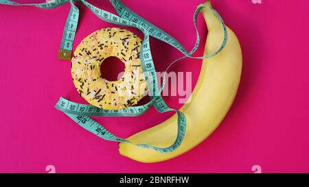 Deux types d'aliments, sains et malsains, banane et beignet, régime et obésité, concept de santé sur fond rose Banque D'Images