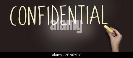 Le mot Confidentiel manuscrit avec craie blanche sur un tableau noir. Concept de confidentialité Banque D'Images