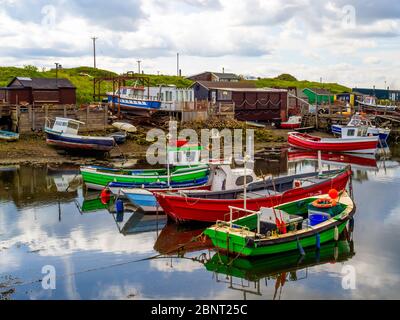 Bateaux de pêche colorés et cabanes de pêcheurs à Paddy's Hole Teesmouth Cleveland UK avec un bateau sur un dérapage pour réparation Banque D'Images