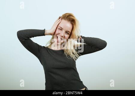 Silly Girl se divertir, tenir la tête avec les mains, en collant hors de sa langue Banque D'Images