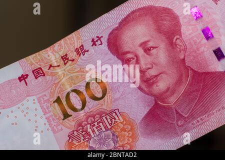 Monnaie de la Chine - une centaine de billets de renminbi ou de yuan rouges répartis sur un fond marron. Change. Banque D'Images