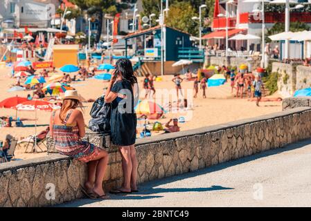 Saint-Palais-sur-Mer, France : deux jeunes femmes sur la promenade regardent la plage animée de la plage du Bureau en haute saison. Banque D'Images