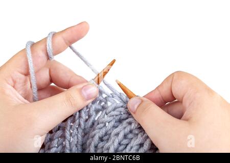 Les mains pour femmes tricotées en laine grise sur fond blanc. Tricotage à la main Banque D'Images