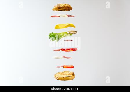 sandwich volant. Couches volantes de sandwich. Patty, jambon, fromage et légumes bien rôtis entre deux moitiés d'un. Concept de la cuisine américaine du petit déjeuner Banque D'Images