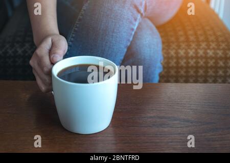 Gros plan image d'une main de femme tenant une tasse de café chaud à boire tout en étant assis dans un café Banque D'Images