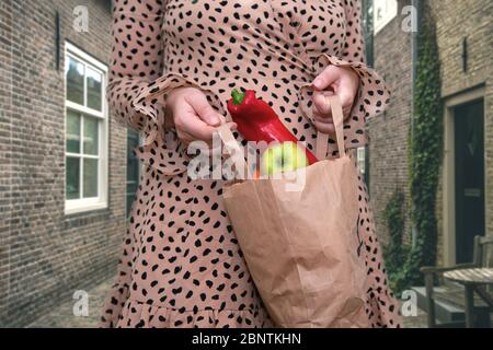 jeune femme tenant un sac de légumes frais et de fruits dans la rue de la ville, des pommes et du poivre Banque D'Images