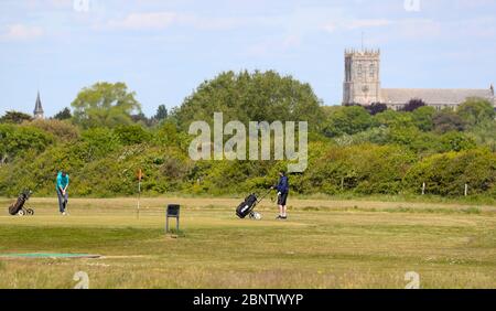 Dorset, Royaume-Uni. 16 mai 2020 les golfeurs jouent au golf 18 trous Pitch & Putt à Solent Meads et regardent le Prieuré de Christchurch tandis que les gens apprécient l'espace et le soleil à Hengistbury Head Beach, loin de la foule à Bournemouth, à 5 kilomètres à l'ouest en bas de la côte. C'est le premier week-end après que l'Angleterre ait assoupli ses mesures de maintien et permis aux gens de voyager plus loin et de faire de l'exercice autant qu'ils le souhaitent. Andrew Fosker / Alamy Live News Banque D'Images