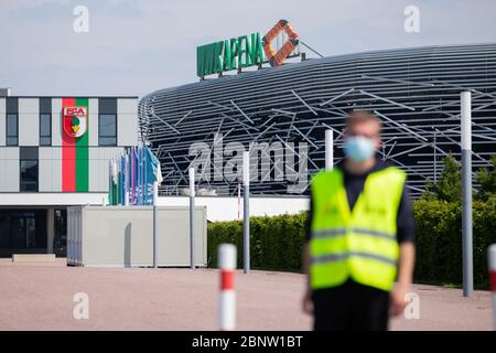 Augsbourg, Allemagne. 16 mai 2020. Un membre du service de sécurité se trouve devant la WWK Arena avec un gardien. Le jeu FC Augsburg - VfL Wolfsburg, comme tous les matchs de la Ligue allemande de football, aura lieu sans spectateurs en raison de la pandémie de corona. Crédit : Tom Weller/dpa/Alay Live News Banque D'Images