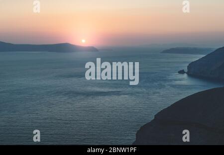 Coucher de soleil avec lumières rouges violettes sur l'océan bleu sur les falaises de Fira, Santorini, Grèce Banque D'Images