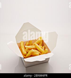 Prise de frites servies dans une boîte en papier sur fond blanc Banque D'Images