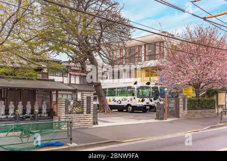 tokyo, japon - mars 30 2020: Jardin d'enfants bouddhiste au printemps avec des cerisiers en fleurs en fleur, des statues jizo bodhisattva et un autobus d'école decora Banque D'Images