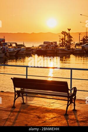 Banc solitaire sur la promenade près de la mer à l'heure du coucher du soleil Banque D'Images