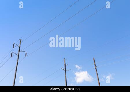 Trois pôles de puissance électrique côte à côte, isolants de contrainte, contre un ciel bleu, aspect horizontal Banque D'Images