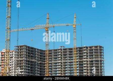 Deux grues de construction près des bâtiments non finis. Construction et développement Banque D'Images