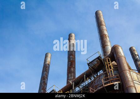 De grandes cheminées roueuses silhouetées sur un ciel bleu vif, un complexe industriel abandonné, un espace de copie, un aspect horizontal Banque D'Images