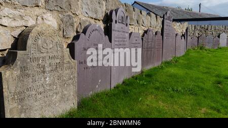 Abergele, Royaume-Uni: 19 août 2019: Le cimetière de l'église Saint-Michel contient ces pierres de tête qui ont été déplacées et qui sont debout contre le boun Banque D'Images