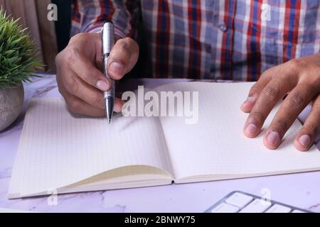 Gros plan de la personne écrivant à la main sur le bloc-notes. Banque D'Images