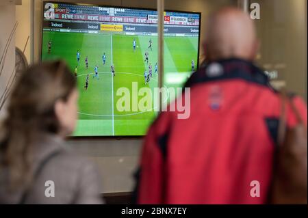 16 mai 2020, Hessen, Francfort-sur-le-main: Deux personnes regardent le match de Bundesliga entre Eintracht Frankfurt et Borussia Mönchengladbach sur un poste de télévision devant un bar sportif de la gare principale. Photo: Silas Stein/dpa Banque D'Images