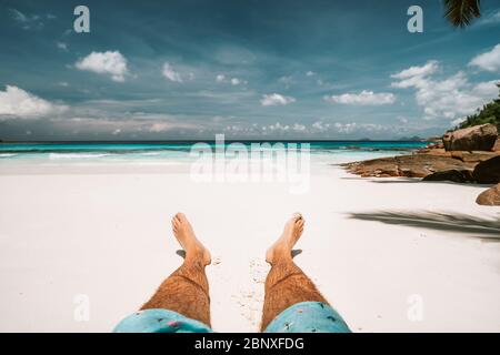 Vacances tropicales. Homme couché et appréciant sur une plage tropicale de sable, l'océan et le ciel bleu Banque D'Images