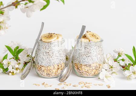 Boudin de graines de Chia avec yaourt et avoine sur fond blanc décoré de fleurs. Concept de superalimentation. Copier l'espace Banque D'Images