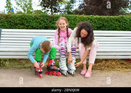 Fille avec maman et frère portant des patins à roulettes dans le Park on t Banque D'Images