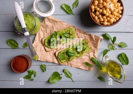 Deux crackers avec humus aux épinards verts sur table en bois. Pose plate. Concept de houmous. Photographie alimentaire Banque D'Images