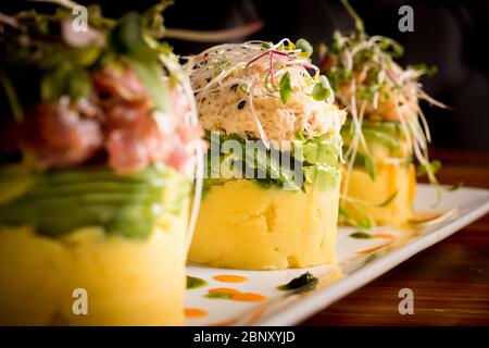 Plat péruvien traditionnel appelé Causa fait de purée de pommes de terre avec le piment et le jus de lime aji et rempli de légumes maïs, pois, carottes et Banque D'Images