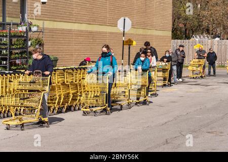 Montréal, CA - 16 mai 2020 : clients d'une ligne à l'extérieur d'un supermarché. Certains portent des masques de protection Covid-19. Banque D'Images