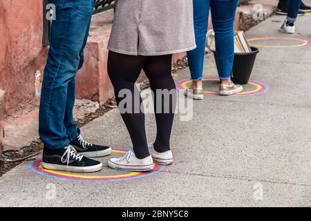 Les clients font la queue devant un magasin, à distance sécuritaire, avec des marques peintes au sol, pendant une pandémie de coronavirus Banque D'Images