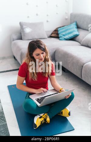 femme faisant du sport sur un tapis suivant des cours en ligne avec un ordinateur portable à la maison Banque D'Images