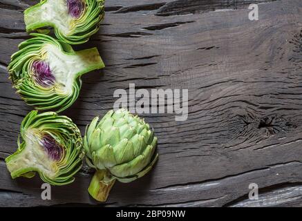 Boutons comestibles de fleurs d'artichaut vert et violet sur fond en bois. Banque D'Images
