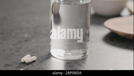 pilules blanches et verre d'eau sur le comptoir en terrazzo Banque D'Images