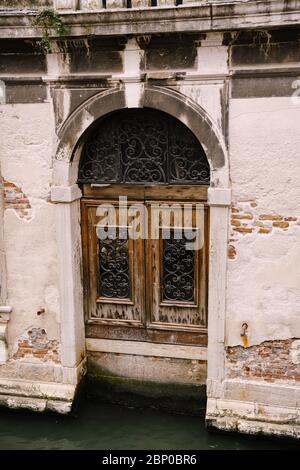Gros plan de la façade d'un bâtiment, dans les rues de Venise, Italie. Entrée de l'eau au bâtiment. Porte en bois antique en métal forgé Banque D'Images