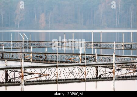 Vieux métal et bois, un peu rouillé plates-formes sur le lac. Piers en bois avec construction en acier peint en blanc. Réflexion sur l'eau. Banque D'Images