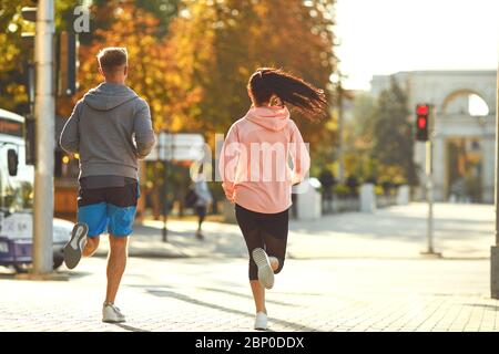 Un homme et une femme sont en marche le long de la rue de la ville dans la matinée. Banque D'Images