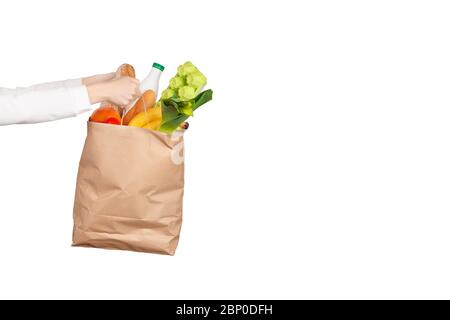 Concept de livraison ou de don de nourriture. Shoping dans l'épicerie. Les mains des femmes ont un sac en papier rempli de produits alimentaires comme les fruits, les légumes, le lait, le yogourt Banque D'Images