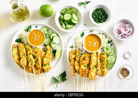 Satay de poulet avec sauce aux arachides. Brochettes de poulet grillées servies avec sauce à la sauce aux cacacahuètes. Repas savoureux pour le dîner ou les hors-d'œuvre de fête. Fond clair Banque D'Images