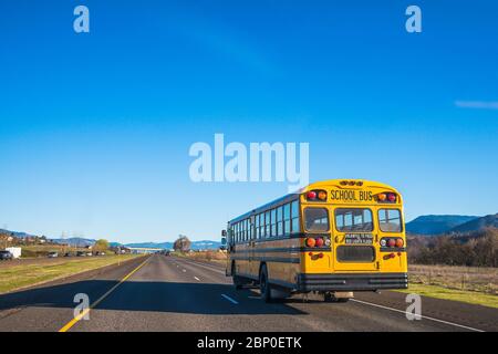 bus scolaire sur la route contre le ciel bleu. Banque D'Images