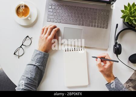 Homme travaillant sur un ordinateur portable et buvant du café sur son lieu de travail. Bureau à domicile, vue du dessus Banque D'Images