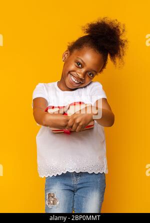 Petite fille afro reconnaissante obtenant cadeau, timide et souriant Banque D'Images